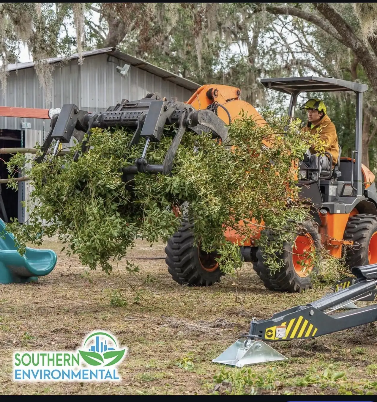 Compact wheel loader with hydraulic grapple moving tree debris
