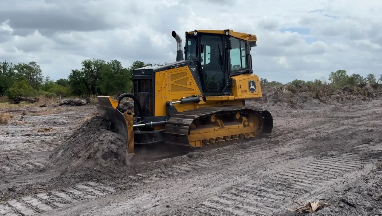 John Deere crawler dozer grading and leveling site after tree removal